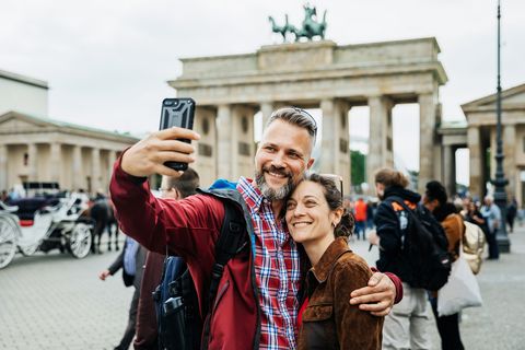 a mature couple take a selfie together in front of brandenburg gate in berlin
