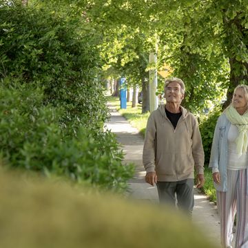 mature couple walk along residential sidewalk
