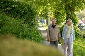 mature couple walk along residential sidewalk