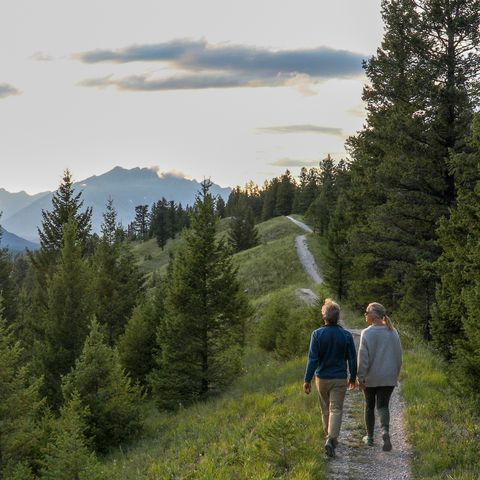 mature couple walk down trail at sunrise