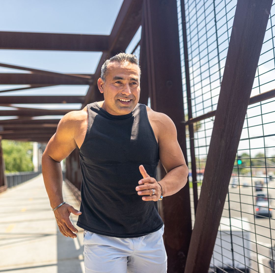 mature hispanic man jogging urban bridge in california