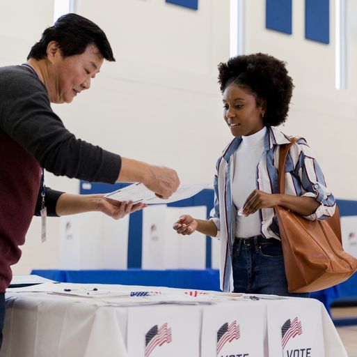 mature male volunteer explains voting document to young woman