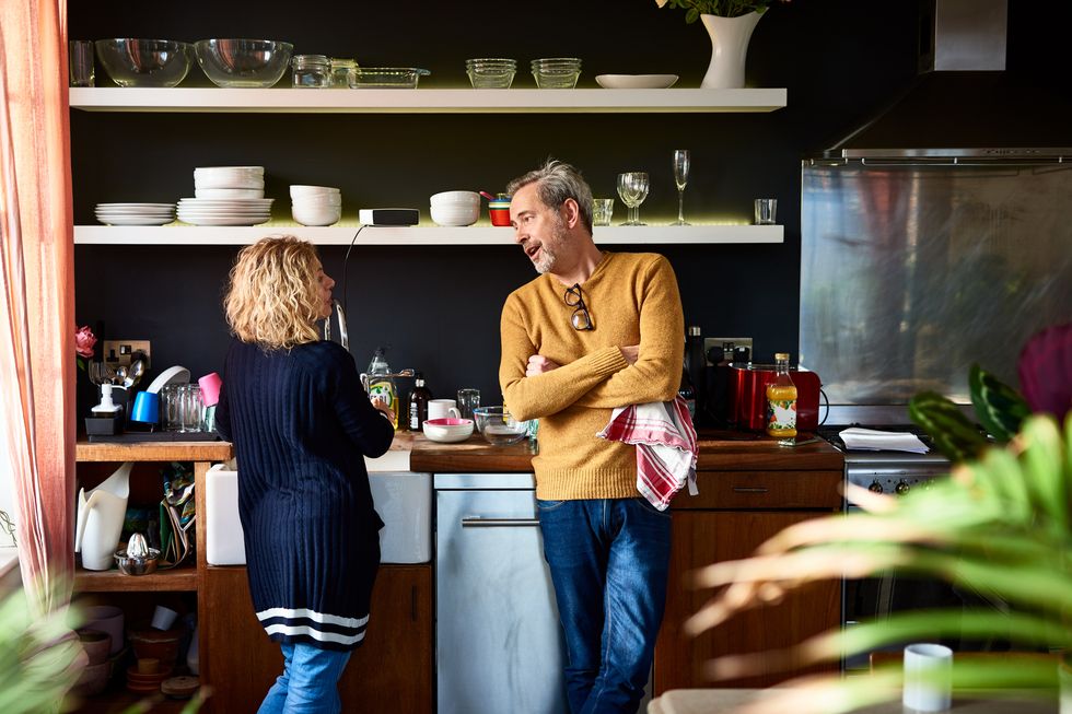 mature man and woman doing dishes together in kitchen