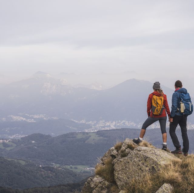 mature man and woman holding hands standing on rock