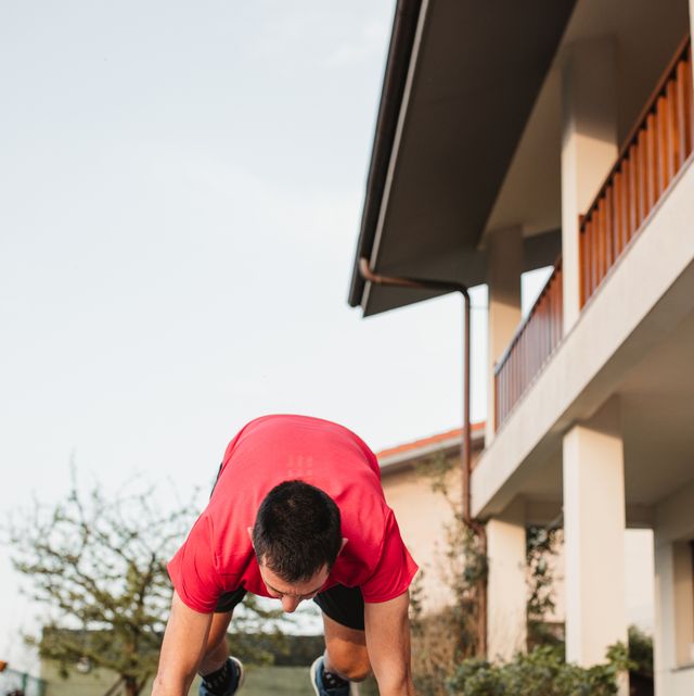mature man doing burpees with sportswear on the terrace of his house at sunset