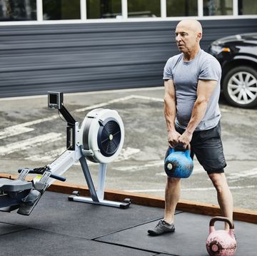 mature man doing kettlebell squats during workout at outdoor gym
