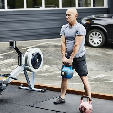 mature man doing kettlebell squats during workout at outdoor gym