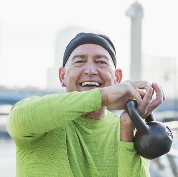 mature man in city, exercising with kettlebell