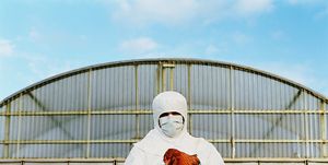 bird flu, mature man in clean suit holding chicken on farm, portrait