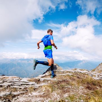 mature man is engaged in trail running in the mountains