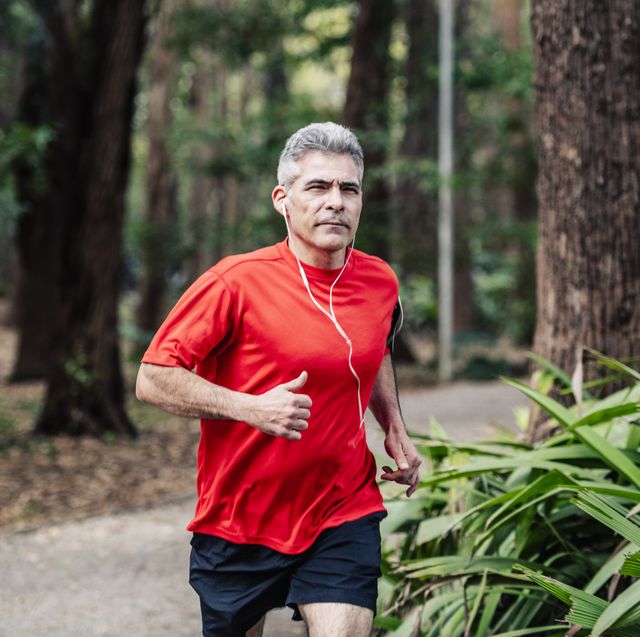 Mature man jogging in woods with earphones