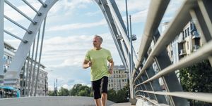 mature man jogging on bridge in city