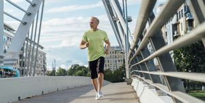 mature man jogging on bridge in city