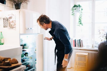 mature man looking into refrigerator while standing at kitchen