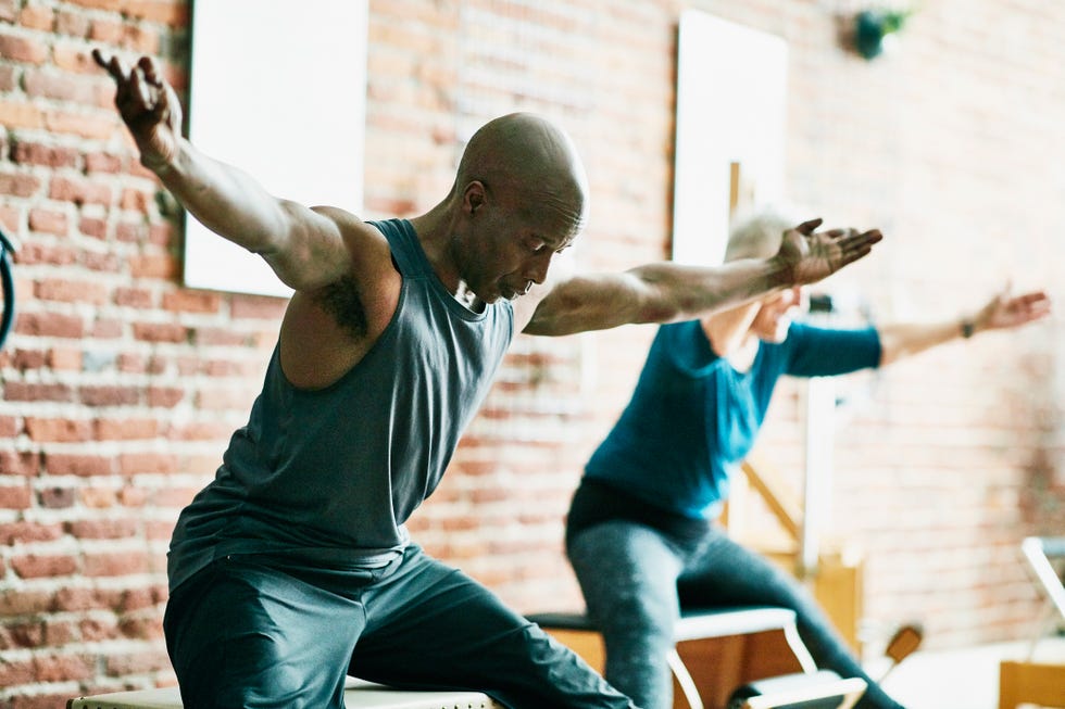 mature man practicing on pilates chair during class in fitness studio