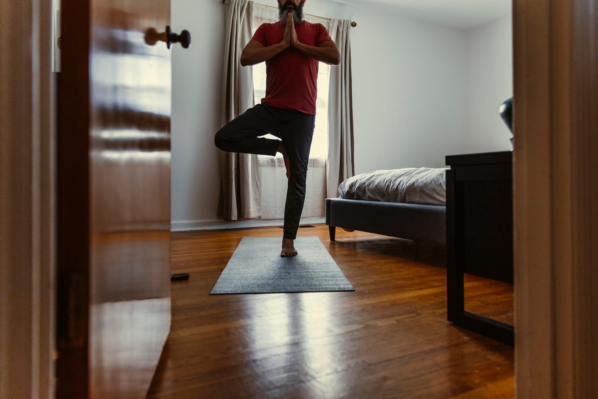 mature man practicing yoga in bedroom