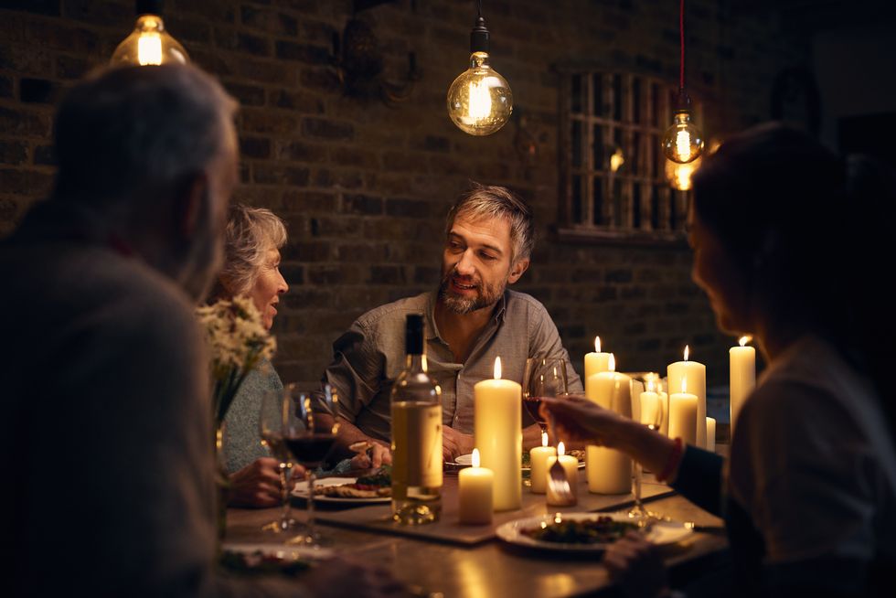 mature man talking to friends at candlelit dinner table