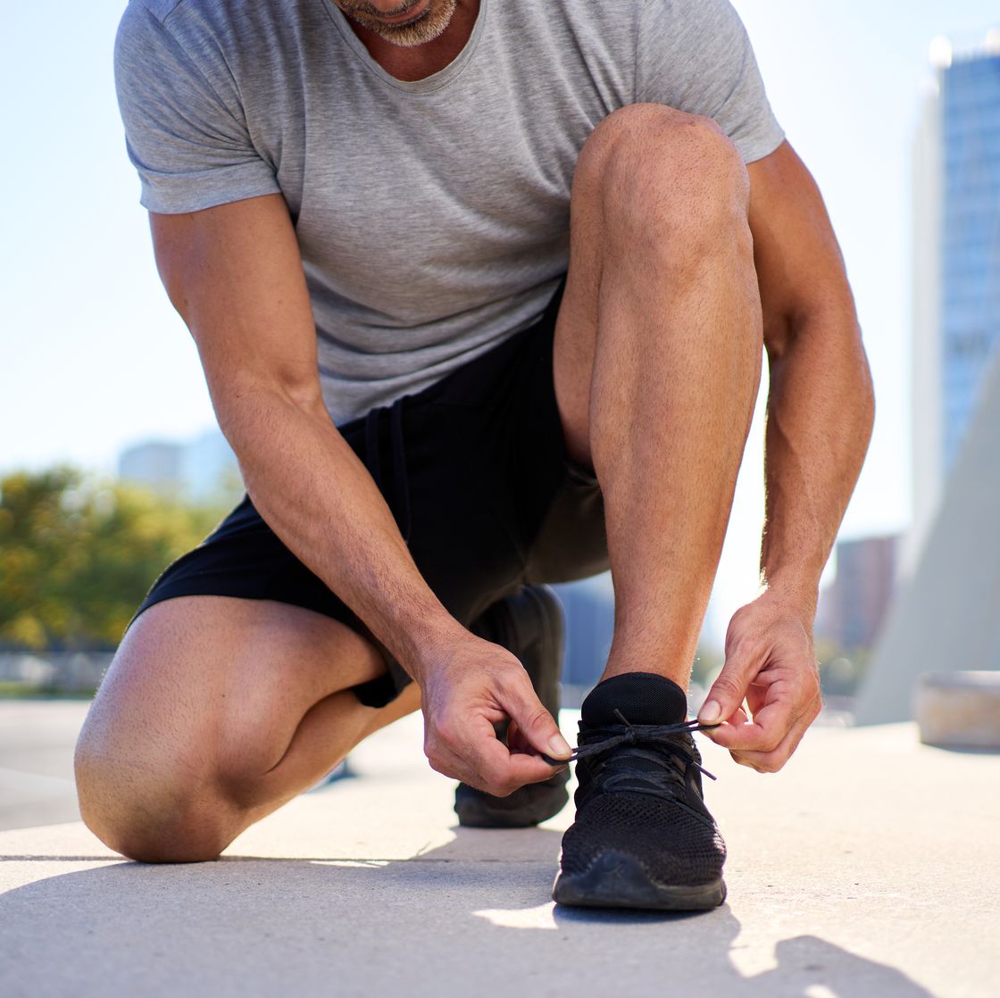 mature man tying shoelaces before running in the city.