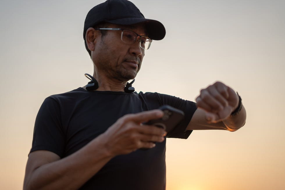 mature man using a smartwatch and doing outdoor workouts in the park
