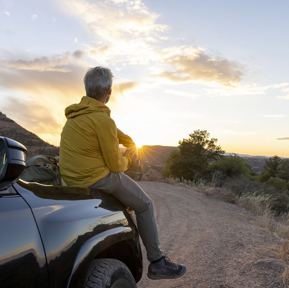 mature man watches sunset from vehicle
