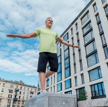 Mature man with arms outstretched exercising on concrete by building mature man with arms outstretched exercising on concrete by building