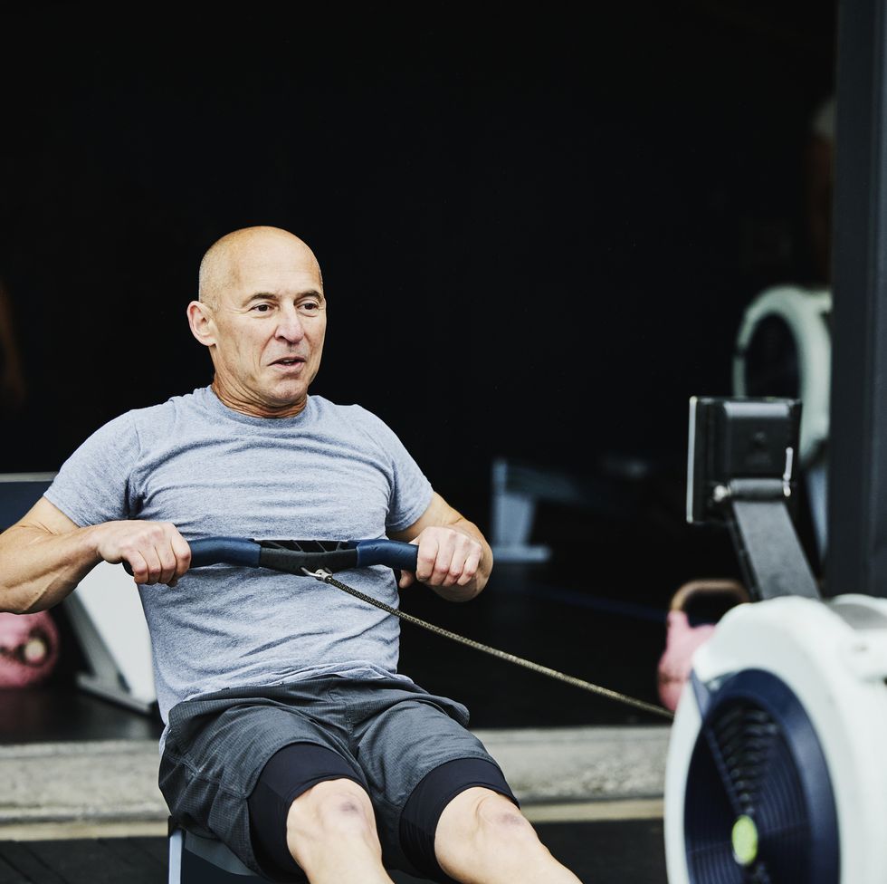 mature man working out on rowing machine at outdoor gym