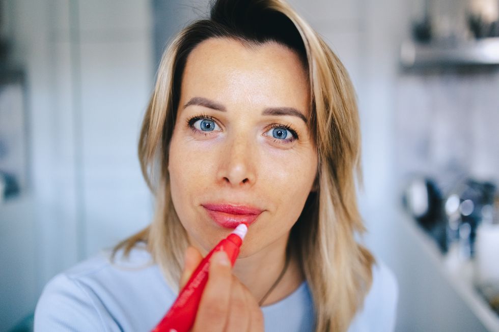 una chica rubia se aplica hidratacion en los labios