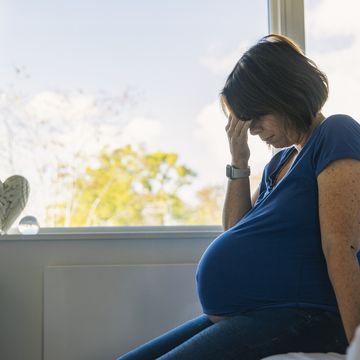 mature pregnant woman sitting on her bed negative emotion