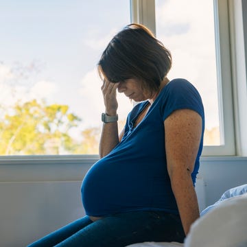 mature pregnant woman sitting on her bed negative emotion