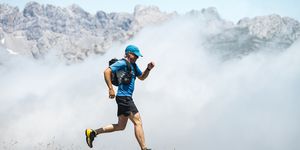 mature sportsman trail running through foggy mountains