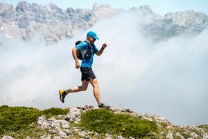 mature sportsman trail running through foggy mountains