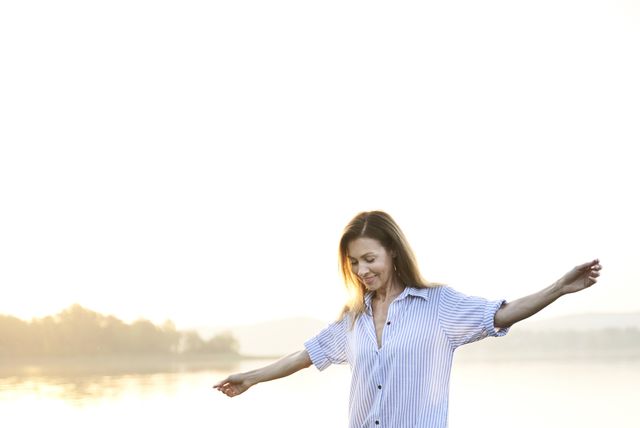 mature woman balancing on jetty at a lake at sunrise