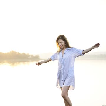 mature woman balancing on jetty at a lake at sunrise
