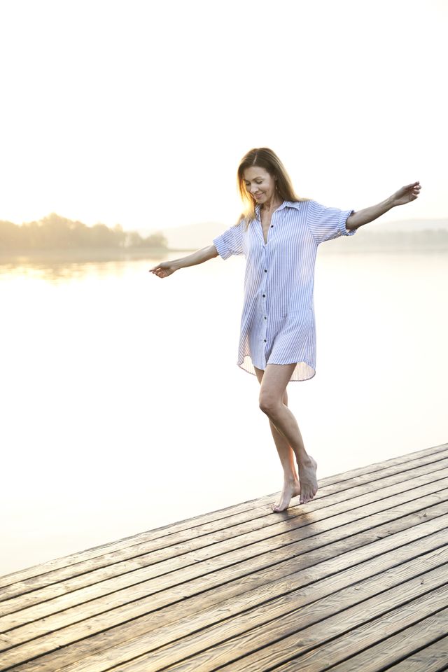 mature woman balancing on jetty at a lake at sunrise