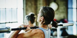 Mature woman doing barbell lifts during workout