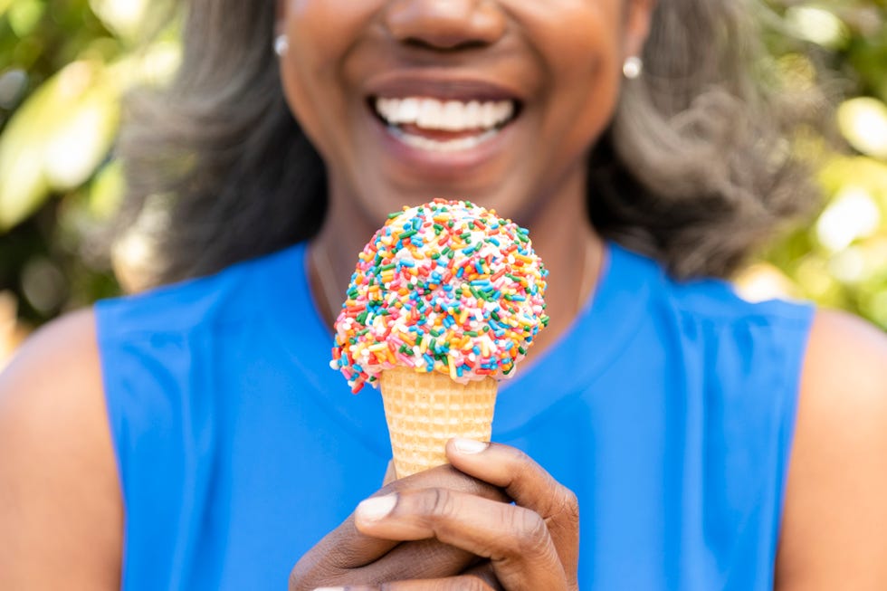 mature woman holding ice cream cone with sprinkles