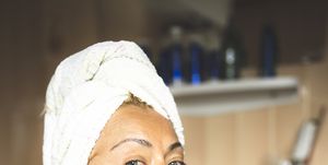 mature woman in bathrobe moisturizing face in bathroom