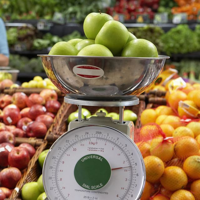 'Mature woman in supermarket, focus on weighing scale'