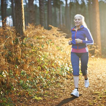 mature woman jogging on forest path
