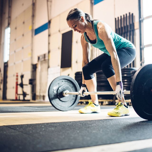 mature woman lifting weights in gym setting