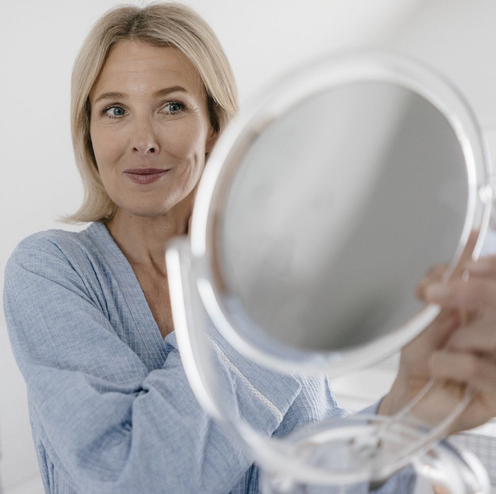 mature woman looking in beauty mirror in bathroom