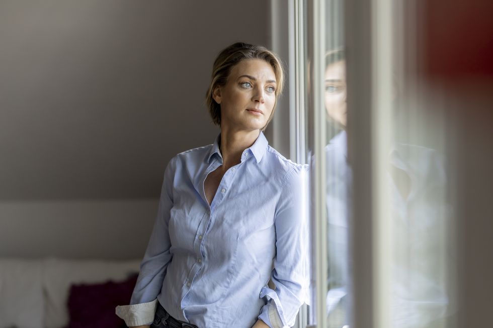 mature woman looking out of the window at home