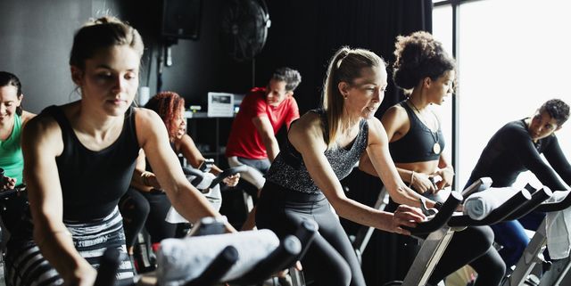 Mature woman participating in cycling class in fitness studio