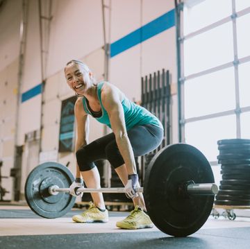 mature woman practicing deadlifts in cross training gym