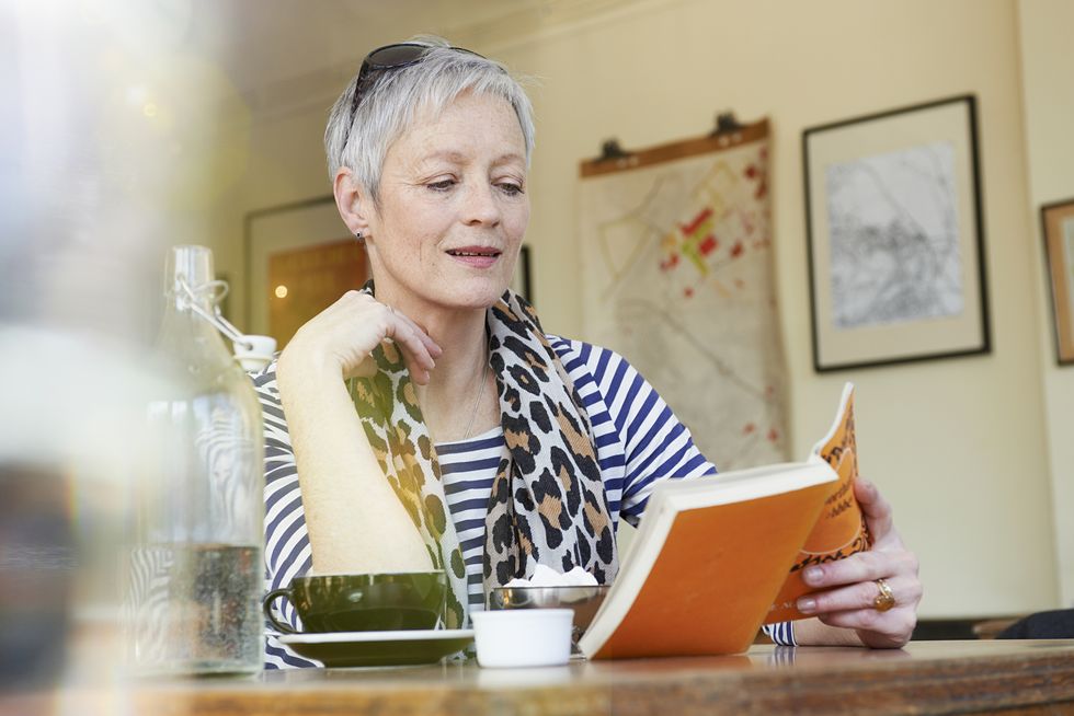 mature woman reading book in cafe