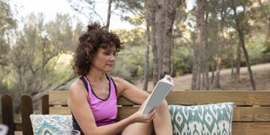 mature woman reading book while siting on bench