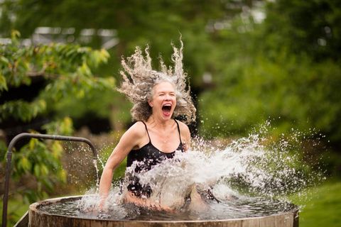 woman splashing into fresh cold water tub
