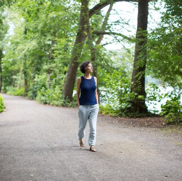 mature woman walking on road in forest
