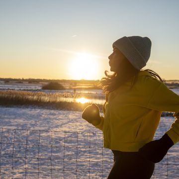 mature woman wearing knit hat running during winter