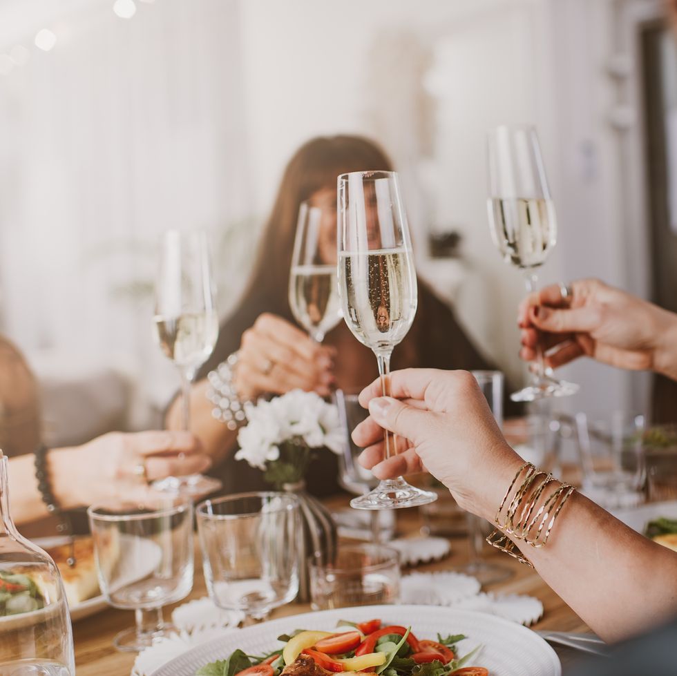 hands toasting champagne flutes over a dinner table